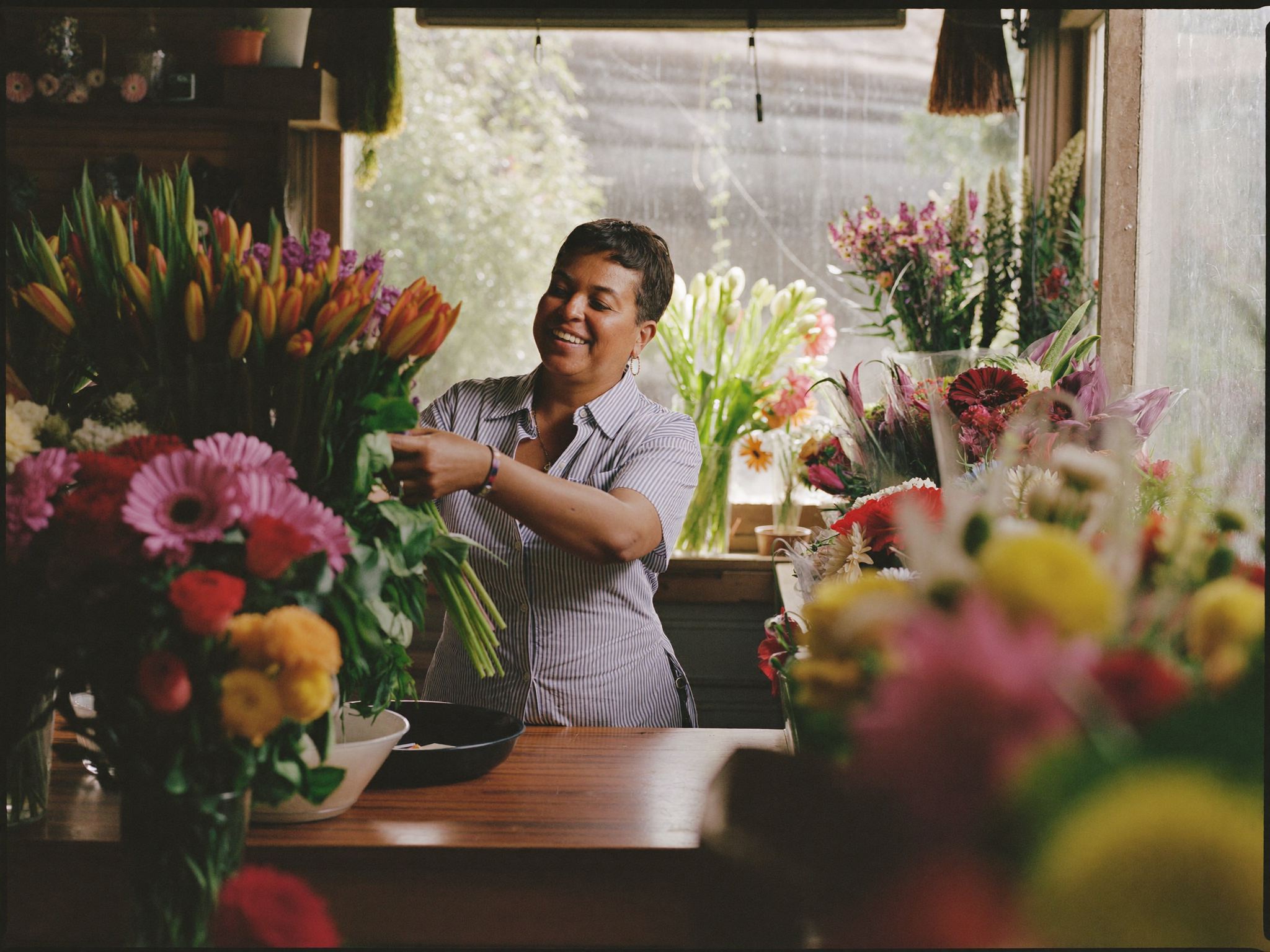 Empreendedora local sorrindo em sua floricultura